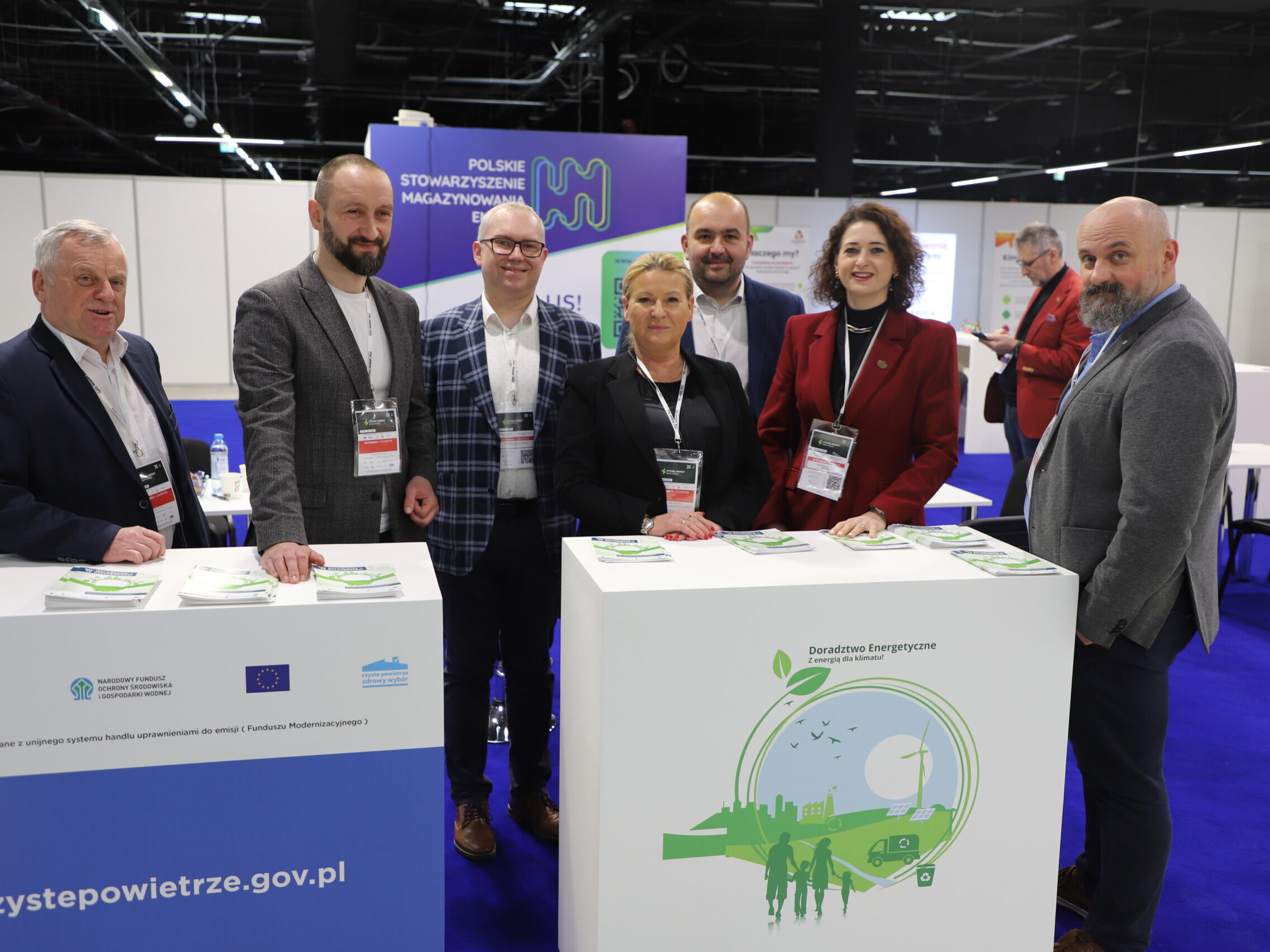 na zdjęciu stoi 8 doradców energetycznych na tle stoiska wystawienniczego