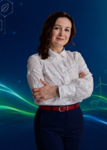 zdjęcie kobiety, do pasa, kobieta ma białą bluzke i granatowe spdnie, Długie ciemne włosy. Stoi z rękami skrzyżowanymi.